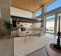 Living space in a family house with stairs, a sofa, and large windows to the terrace.