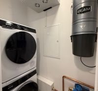 Laundry room in a family house: washing machine, dryer, BEAM central vacuum, and water filter.