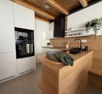 A kitchen in a family house with wooden decor, white cabinets, and plants.