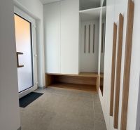 Entrance hall in a family house with a mirror, storage space, and light tiles.