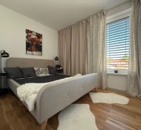 Bedroom with a bed, curtains, painting, and a wooden decor floor in a family house.