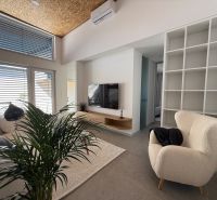 Living room in a family house with a cream armchair and a television, wooden decor flooring.