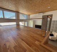 Interior of a family house with a wooden decor floor and large windows.