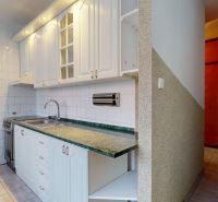 A kitchen in a 3-room apartment with white cabinets and a green countertop.