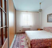 A bedroom in a three-room apartment with carpet decor and a painting on the wall.