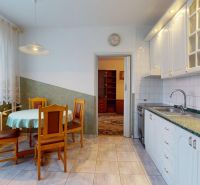 A kitchen in a 3-room apartment with a dining table, white cabinets, and a green countertop.
