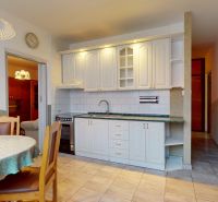 A kitchen in a 3-room apartment with a dining area and white cabinets.