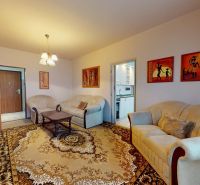 Living room in a 3-room apartment with light furniture and a decorative carpet.