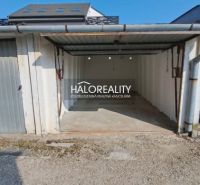 Garages in Senec with a metal gate and gravel access.