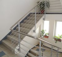 A staircase in the office with stainless steel railing, flowers, and large windows.