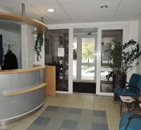 Reception with wooden decor, seating, and plants in offices.