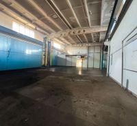Production spaces with high ceilings, featuring light blue doors and pipes on the walls.