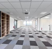 An office interior with carpet tiles, glass walls, and wooden decor.
