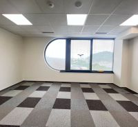 Empty office with a window, gray patterned carpet, and a view of the mountains.