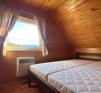 A room with wooden decor, a bed, and a view from the window in the Cottage.