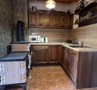A kitchen in a cabin with wooden decor and a stove, a combination of wood and stone.