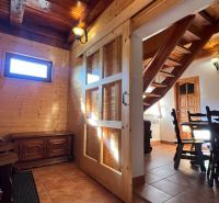 Wooden interior with a dining table, staircase, and wooden decor on the wall.