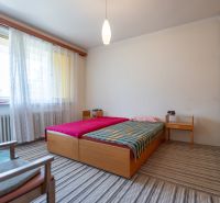 Bedroom with a light carpet and a bed in a 3-room apartment.