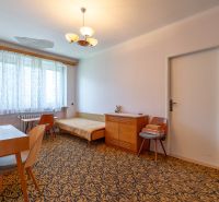 A room with a carpet, a desk, a bed, and cabinets in a three-room apartment.