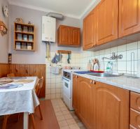 A kitchen in a 3-room apartment with wooden cabinets and a dining table.