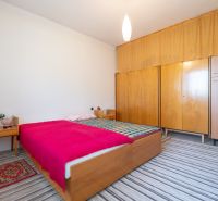 A bedroom in a three-room apartment with wooden furniture and a striped carpet.