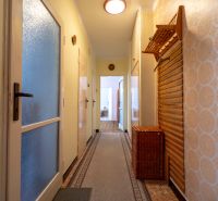 A hallway of a 3-room apartment with patterned wallpaper, a built-in wardrobe, and a carpet runner.