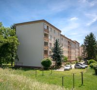 Apartment buildings on Švermova Street in Trenčín with surrounding greenery and parked cars.