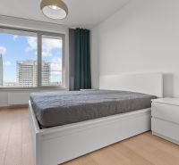 A bedroom in a 3-room apartment with a view of the city buildings on Továrenská Street.