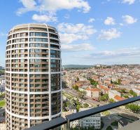 View from the balcony on Továrenská Street, with a panorama and a high-rise building.