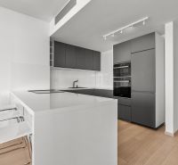 A minimalist kitchen in a 3-room apartment on Továrenská Street with modern equipment and bar stools.