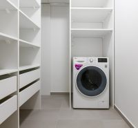 A spacious laundry room with shelves and a washing machine in an apartment on Továrenská Street.