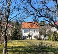 A family house in Podháj, Kráľová, surrounded by trees and lawn, with an orange roof.