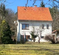 A family house in Kráľová, Banská Bystrica, with a red roof surrounded by greenery and trees.