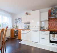 A kitchen in a family house with white cabinets and a wood-patterned floor.