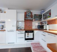 A kitchen in a family house with white cabinets and a wooden decor floor.