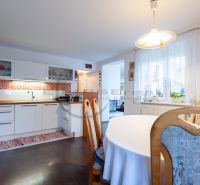 A kitchen in a family house with white cabinets, orange tiles, and a wood-patterned floor.