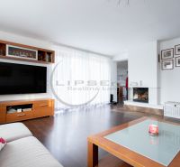 Living room in a family house with a fireplace, television, and wooden decor flooring.
