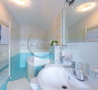 A bathroom in a family house with a white sink, bathtub, mirror, and towel rack.