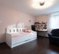 Children's room with a white bed, desk, chair, and floor with wooden decor.