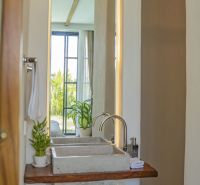 Bathroom in the villa with a mirror, sink, plants, and a view of the garden.