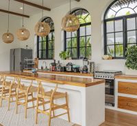 A kitchen in a villa with a bar counter, wooden chairs, and large windows.