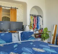 A bedroom in a villa with a bed, green plants, and an open wardrobe.