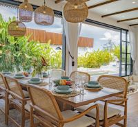 Dining room in the villa with a view of the garden and terrace, floor with wooden decor.