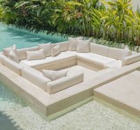 Seating in the pool at a villa in Bali with white cushions and greenery.