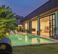 Villa in Bali with a lit pool, terrace with wooden decor, and garden.