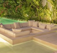 Luxurious outdoor sofa surrounded by tropical greenery by the pool in a villa in Bali.