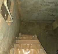 The staircase leading to the basement with walls featuring visible pipes in the Gardens.