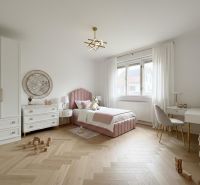 Children's room with wood decor flooring, pink bed, and toys in a family house.