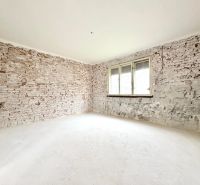 Interior of a family house with bare brick walls and a white floor.