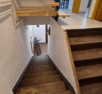 A staircase in a 2-room apartment with a wooden decor and a bicycle at the entrance.